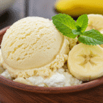 A scoop of creamy banana cottage cheese ice cream garnished with banana slices and mint in a bowl.
